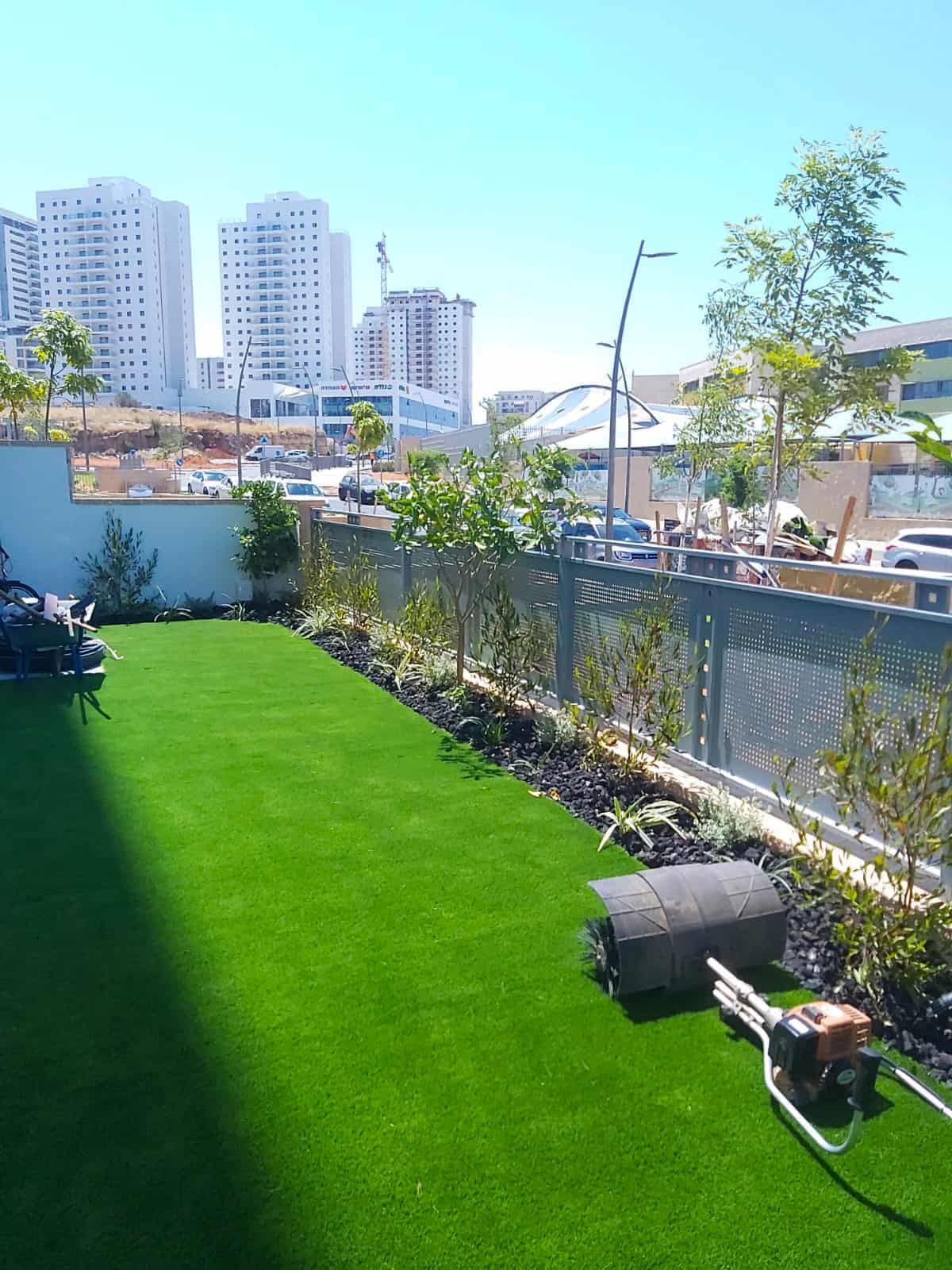 אותה חצר לאחר התקנת דשא סינטטי, צמחייה וניקוי השטח.