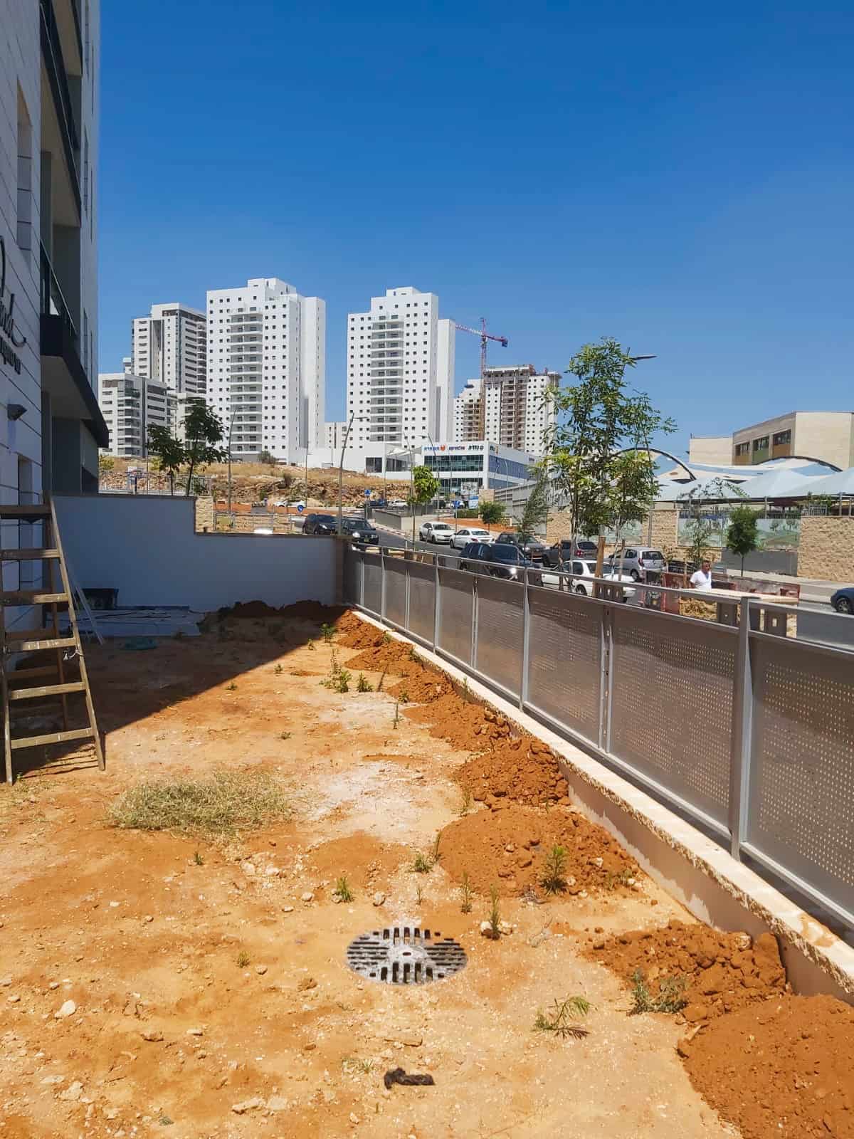 מרפסת או חצר לפני התקנת דשא, עם אדמה חשופה ועשבים.
